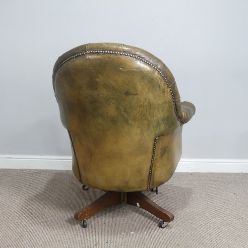 570 - A deep button-back leather swivel desk Chair, scroll arms above serpentine front seat, raised on cas... 