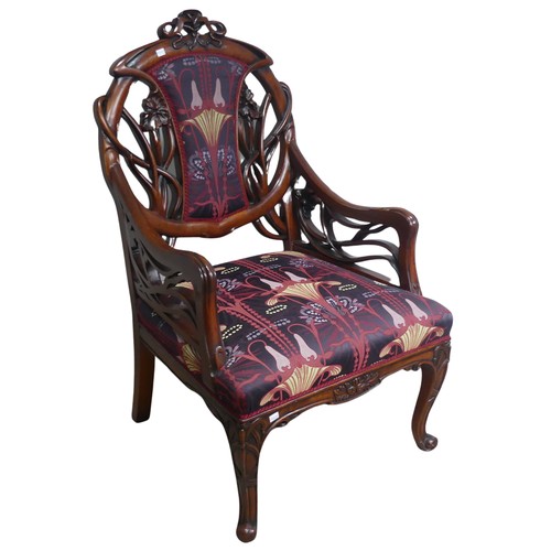 714 - An Art Nouveau style carved mahogany upholstered Armchair, back rest with scrolled and pierced styli... 