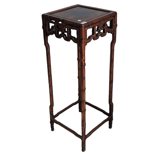 141 - An antique Chinese hardwood Plant Stand, square top above carved foliate frieze, raised on bamboo st... 