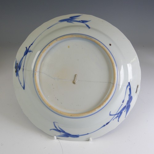 17 - A near pair of early 18thC Chinese porcelain blue and white Plates, the well decorated with flower b... 