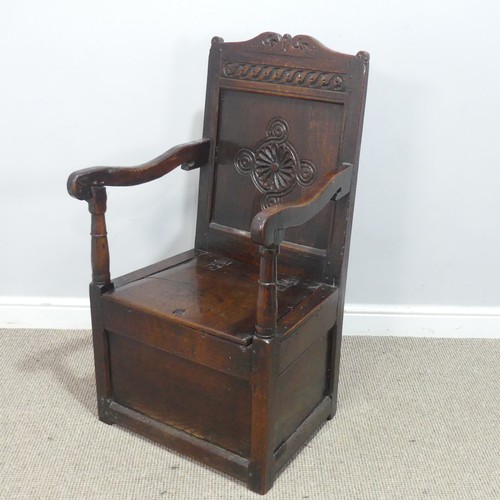 An antique probably 17th century oak wainscot box seat Armchair, carved backrest flanked by scrolled and squared arms, above hinged seats and enclosed supports, the back of the chair stamped 'TS', W 56 cm x H 103.5 cm x D 54 cm.