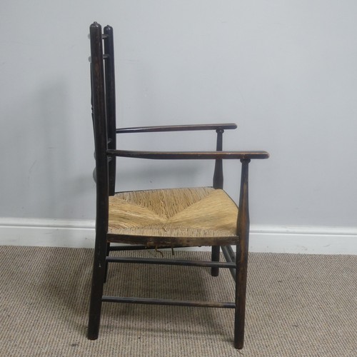 553 - In the manner of William Morris, an antique ebonised Sussex Chair, with turned bobbin back and rush ... 