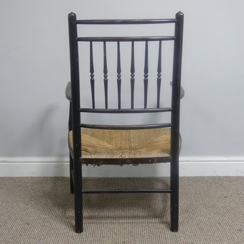 553 - In the manner of William Morris, an antique ebonised Sussex Chair, with turned bobbin back and rush ... 