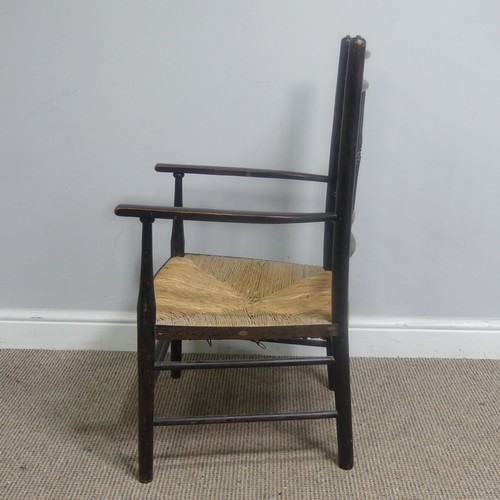 553 - In the manner of William Morris, an antique ebonised Sussex Chair, with turned bobbin back and rush ... 