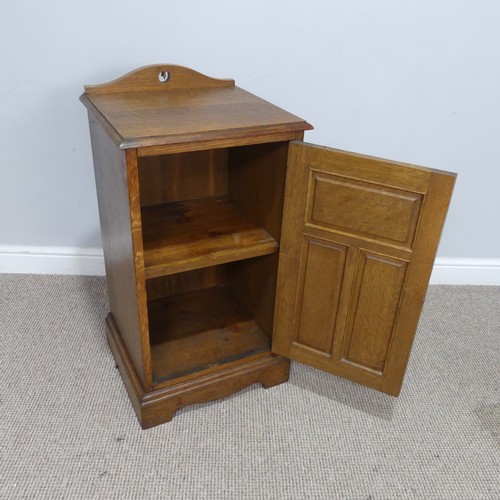 558 - An Arts and crafts oak bedside Cabinet, pierced top over panelled doors, raised on shaped plinth bas... 