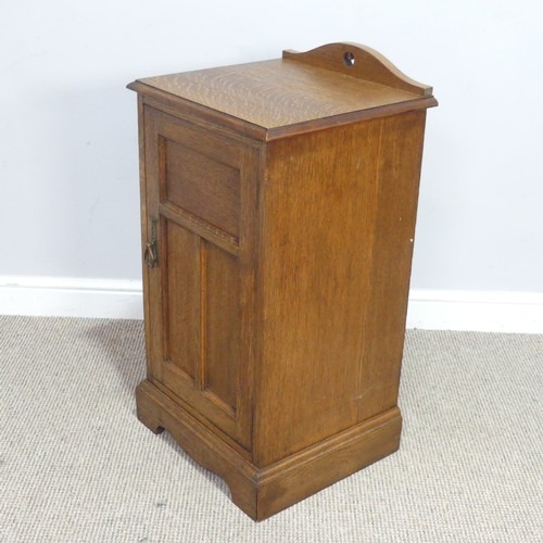 558 - An Arts and crafts oak bedside Cabinet, pierced top over panelled doors, raised on shaped plinth bas... 