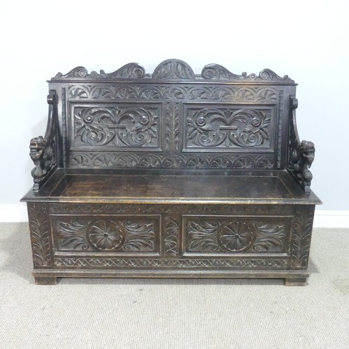 580 - A late Victorian carved oak Settle, foliate carved backrest flanked by scroll arms in the form of dr... 