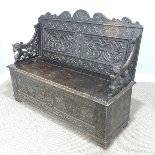 580 - A late Victorian carved oak Settle, foliate carved backrest flanked by scroll arms in the form of dr... 