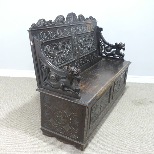 580 - A late Victorian carved oak Settle, foliate carved backrest flanked by scroll arms in the form of dr... 