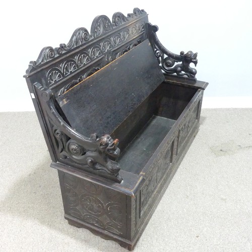 580 - A late Victorian carved oak Settle, foliate carved backrest flanked by scroll arms in the form of dr... 