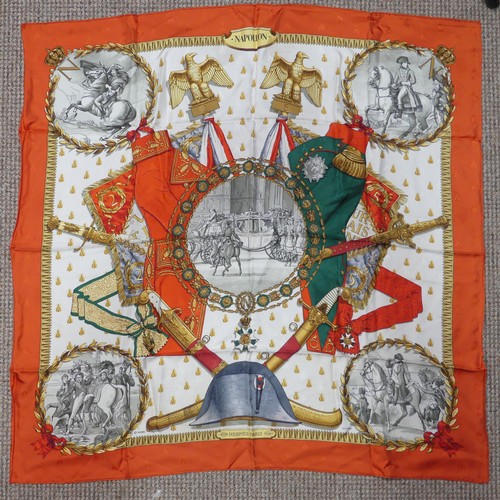 A Hermès jacquard silk scarf: 'Napoleon', designed by Philippe Ledoux, first issued in 1963, featuring a combination of imperial symbols and Napoleonic legend, on a cream background within a dark orange border, with the emperor's beloved bees screened and woven into the silk, hand rolled edges, with fabric composition and cleaning instruction label, approx. 90cm x 90cm, un-boxed.