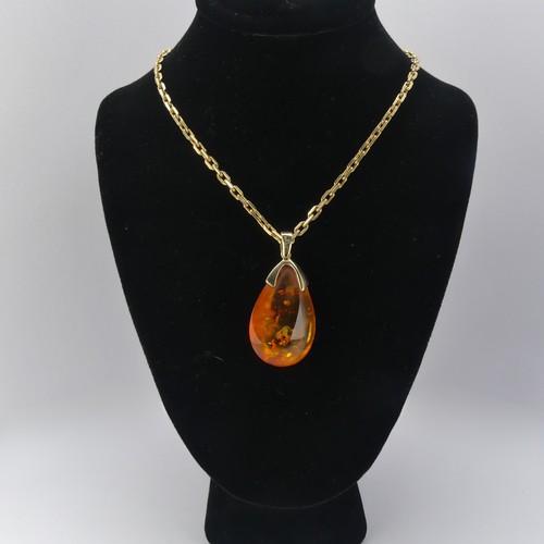 226 - A modern 9ct gold mounted amber Pendant, the reconstituted tear drop shaped stone, 3.2cm long, on a ... 