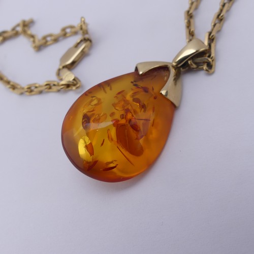 226 - A modern 9ct gold mounted amber Pendant, the reconstituted tear drop shaped stone, 3.2cm long, on a ... 