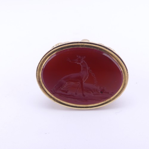 349 - An antique gold plated fob Seal, the oval carnelian matrix carved with a pair of tethered dogs, the ... 