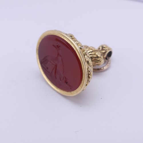 349 - An antique gold plated fob Seal, the oval carnelian matrix carved with a pair of tethered dogs, the ... 