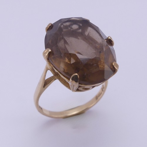 217 - A smoky quartz Dress Ring, the oval facetted stone 19.7mm long, six claw set in 9ct yellow gold, Siz... 