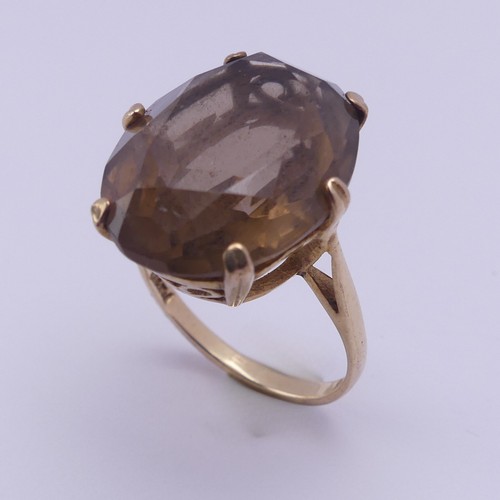 217 - A smoky quartz Dress Ring, the oval facetted stone 19.7mm long, six claw set in 9ct yellow gold, Siz... 