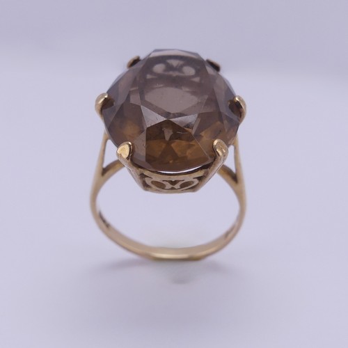 217 - A smoky quartz Dress Ring, the oval facetted stone 19.7mm long, six claw set in 9ct yellow gold, Siz... 