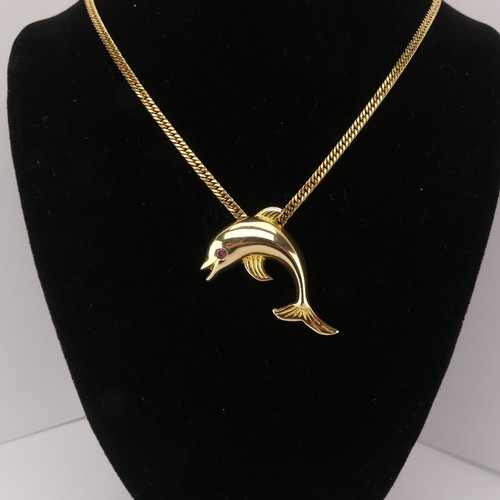 261 - A 14ct yellow gold Dolphin Pendant, with ruby eye, 3.3cm wide, 4.3g, on a 9ct gold curb link chain, ... 