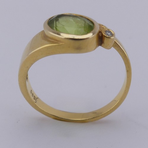 169 - An oval facetted peridot Ring, collet set in 14ct yellow gold with diamond point accent, Size M, 3.3... 