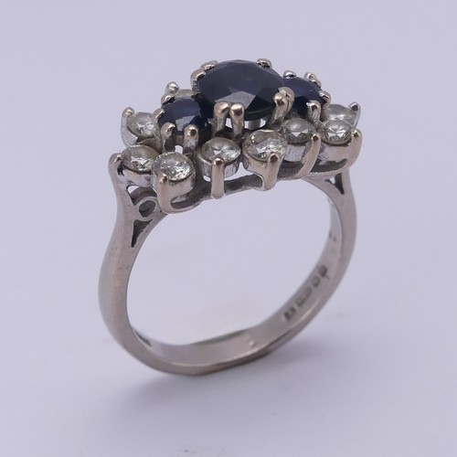 174 - A sapphire and diamond cluster Dress Ring, the centre with three graduated circular facetted sapphir... 