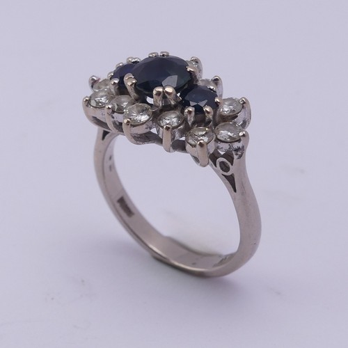 174 - A sapphire and diamond cluster Dress Ring, the centre with three graduated circular facetted sapphir... 