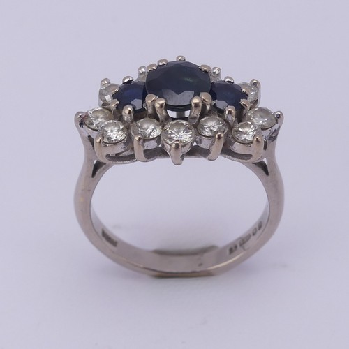 174 - A sapphire and diamond cluster Dress Ring, the centre with three graduated circular facetted sapphir... 