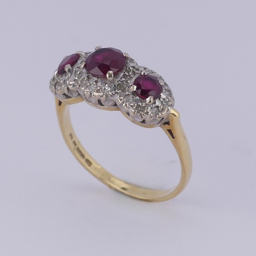 182 - A ruby and diamond triple cluster Ring, the graduated circular facetted rubies surrounded by small d... 