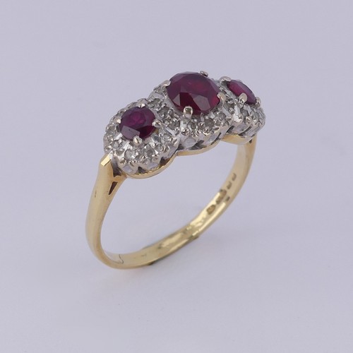 182 - A ruby and diamond triple cluster Ring, the graduated circular facetted rubies surrounded by small d... 