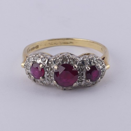 182 - A ruby and diamond triple cluster Ring, the graduated circular facetted rubies surrounded by small d... 