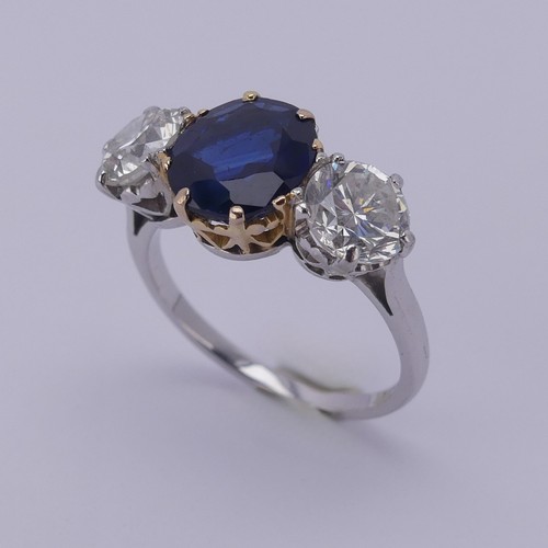 301 - A sapphire and diamond three stone Ring, the central cushion shaped facetted sapphire, approx. 2.6ct... 