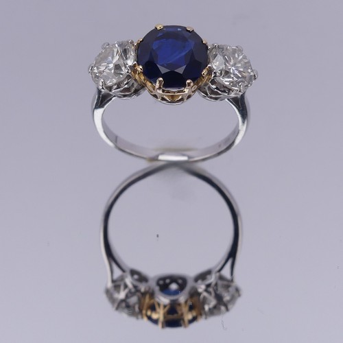 301 - A sapphire and diamond three stone Ring, the central cushion shaped facetted sapphire, approx. 2.6ct... 