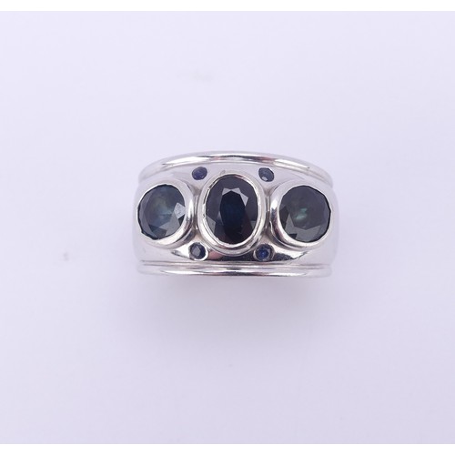 198 - A contemporary three stone sapphire Ring, the oval facetted stones, each approx. 6.2mm long, collet ... 