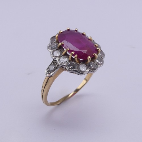 202 - A ruby and diamond cluster Ring, the central oval ruby approx. 11.4mm long, claw set above a surroun... 