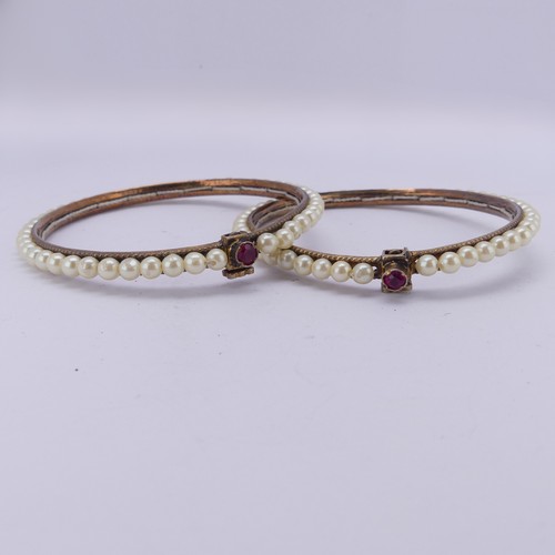 294 - A pair of vintage Bracelets, probably Indian, decorated with faux pearls, the clasps each set ruby a... 