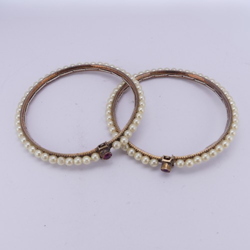 294 - A pair of vintage Bracelets, probably Indian, decorated with faux pearls, the clasps each set ruby a... 