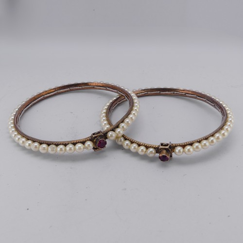 294 - A pair of vintage Bracelets, probably Indian, decorated with faux pearls, the clasps each set ruby a... 