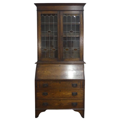 355 - An Arts and Crafts oak bureau Bookcase, cornice over lead framed stained glass, raised on Bureau bas... 