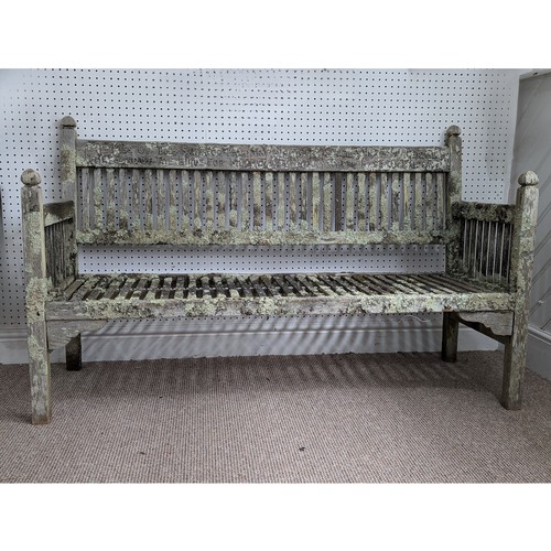 391 - A rare Edwardian teak garden Bench by Heals of London, circa 1900, having decorative ball finials to... 