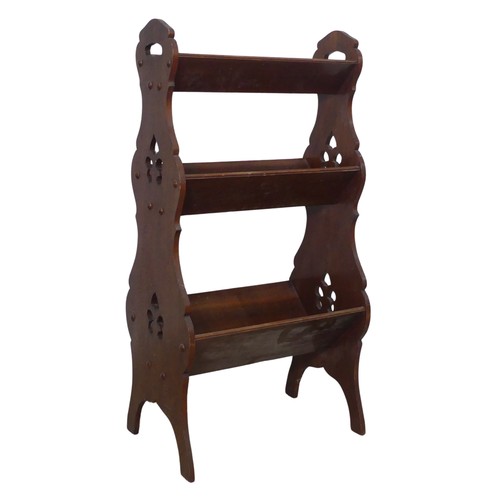 369 - An Arts and Crafts three tiered Book Trough / Magazine Rack, with pierced carrying handles and decor... 