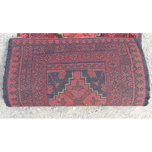 554 - Tribal Rugs: two small Afghan red-ground runners, both approx. 148cm x 52cm and in good condition (2... 