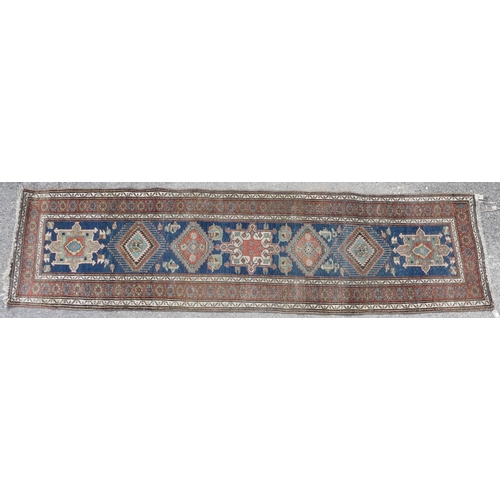 563 - Tribal rugs; a hand-knotted blue ground Caucasian Runner, wool pile on cotton and wool base, with da... 