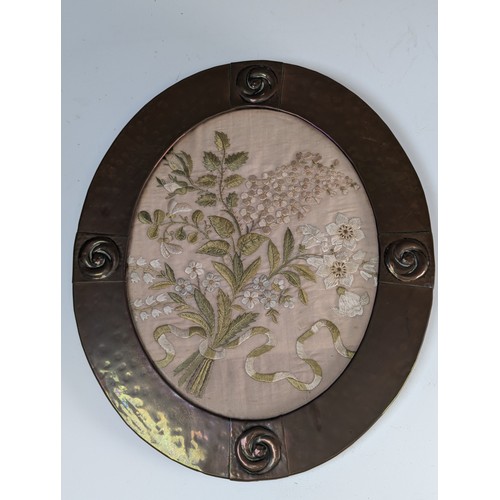 532 - An Arts & Crafts copper oval frame with stylised floral Embroidery, W 27 cm x H 32 cm.... 