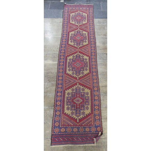 568 - Tribal Rugs; a Sumak Runner, red and blue ground, 100% wool, 288cm x 65cm.