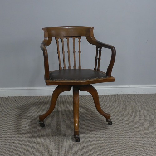 514 - An early 20th century Arts and Crafts style captains swivel desk Chair, shaped backrest and shaped s... 