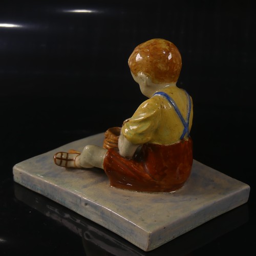 54 - Isobel Holland (1913-1986) a Clevedon Pottery figure of a Boy, modelled sat upright potting with a t... 