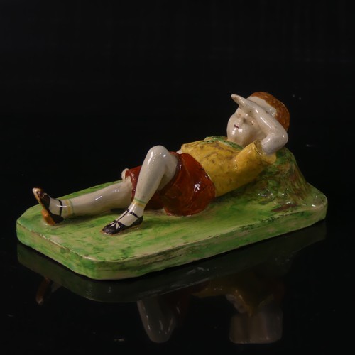 55 - Isobel Holland (1913-1986) a Clevedon Pottery figure of a Boy, modelled laying in the grass with arm... 