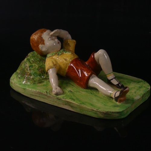 55 - Isobel Holland (1913-1986) a Clevedon Pottery figure of a Boy, modelled laying in the grass with arm... 