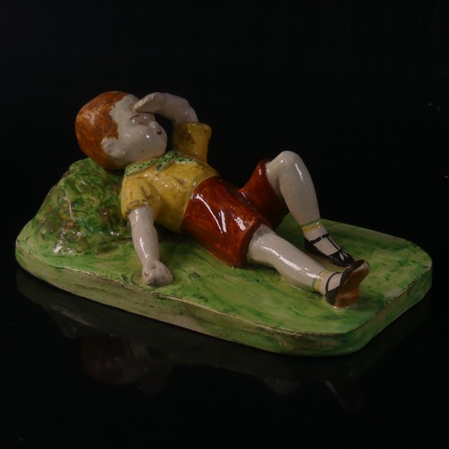 55 - Isobel Holland (1913-1986) a Clevedon Pottery figure of a Boy, modelled laying in the grass with arm... 