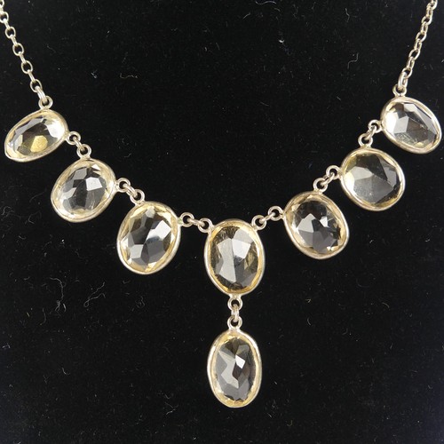 257 - A vintage citrine Necklace, the seven oval facetted stone with one further suspended below collet se... 